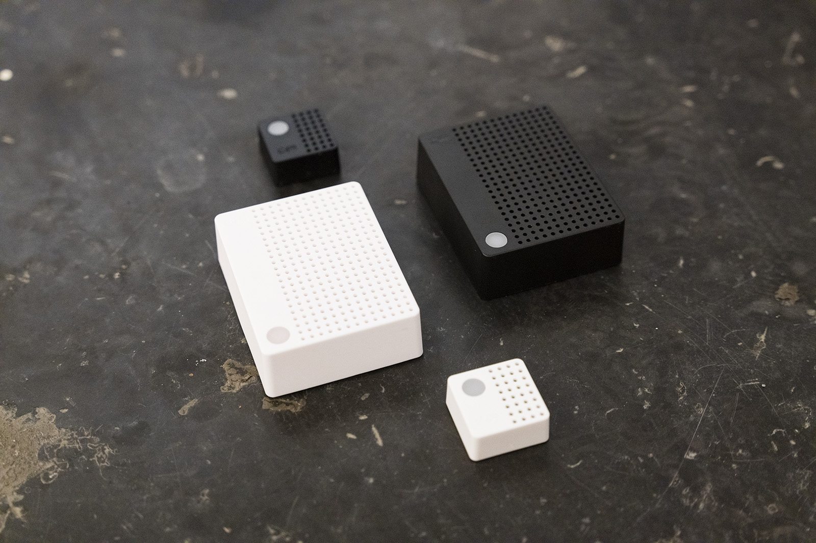 Charp Maxi and Mini loggers in black and white arranged on a dark stone surface.