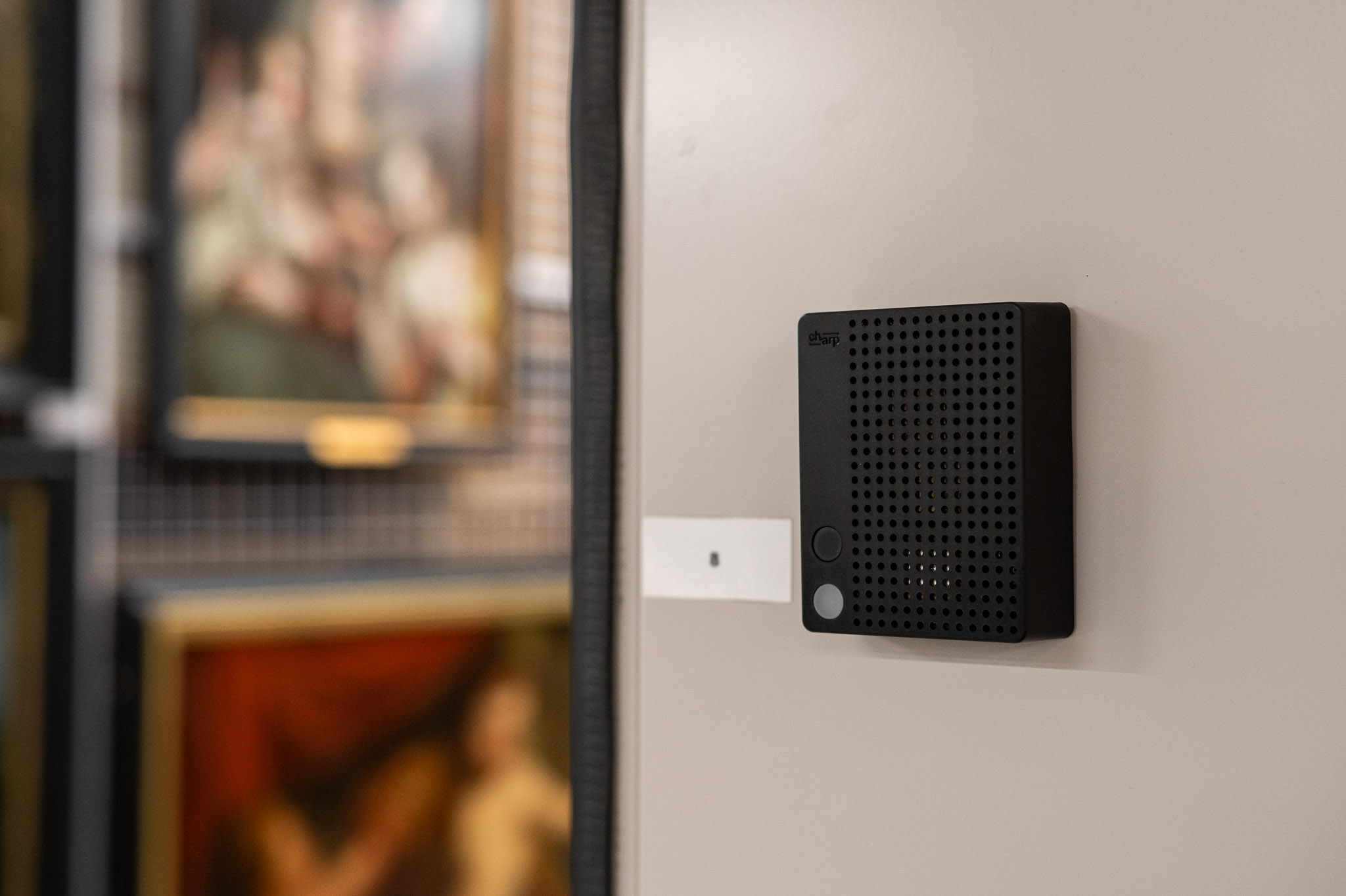 A black Charp Maxi logger mounted on a wall next to framed old master paintings at M Leuven.