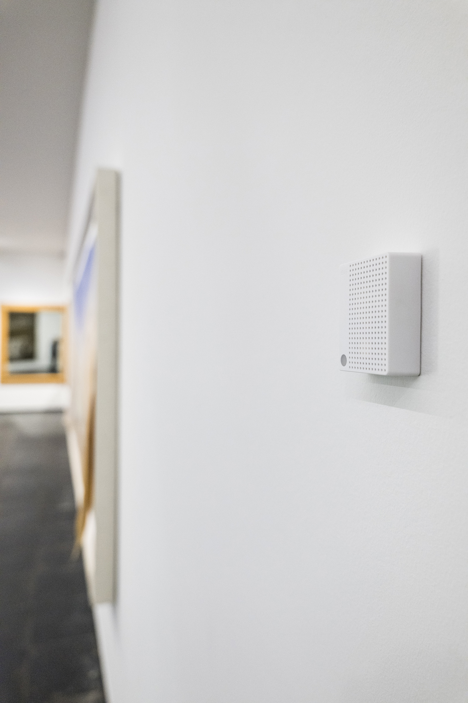 A white Charp Maxi logger on a plain gallery wall next to a framed work at S.M.A.K. in Ghent.