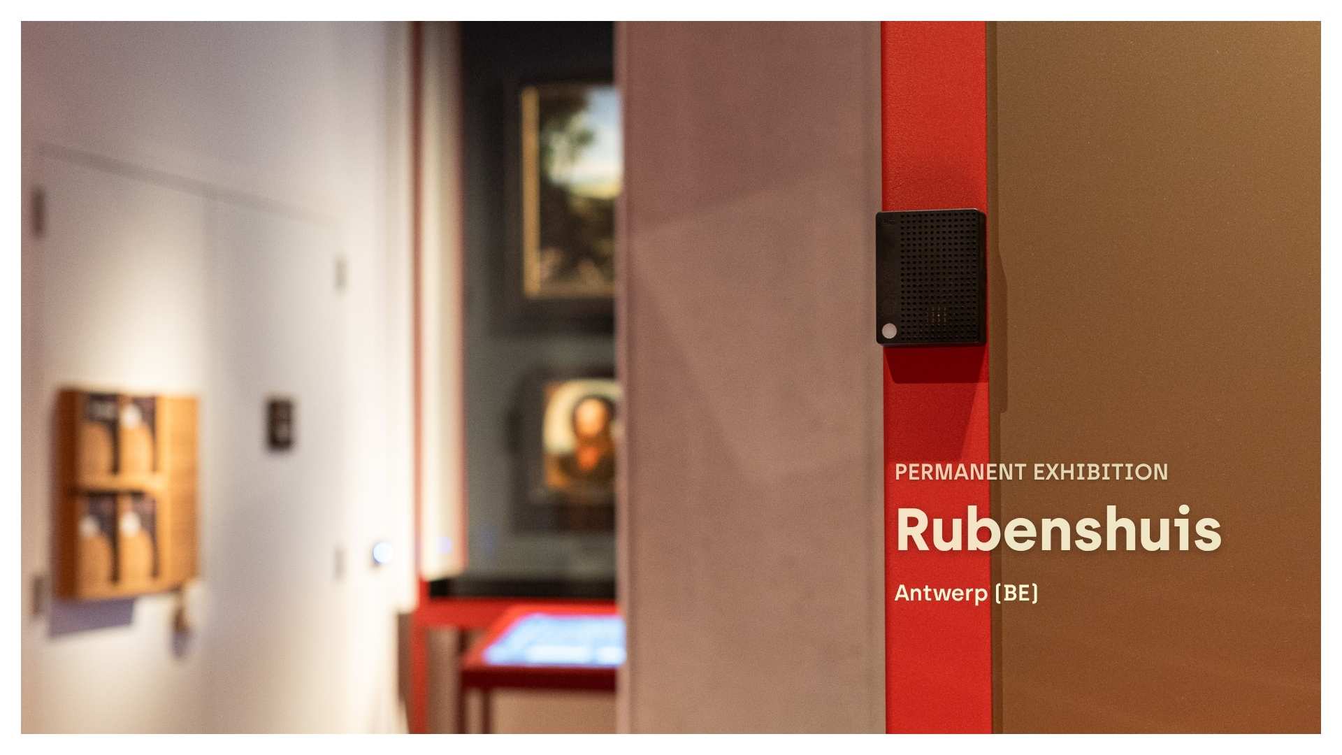 A black Charp Maxi logger fixed to a gallery wall beside framed paintings in the permanent exhibition at the Rubenshuis, Antwerp.